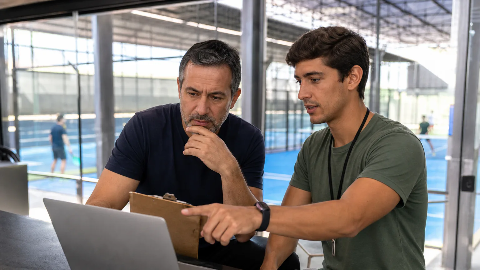 Gestor e especialista avaliam um sistema de gestão em um notebook diante das quadras